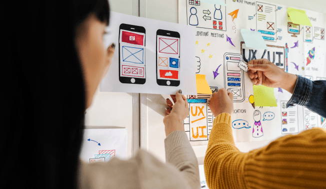 Team collaborates on UX/UI design, using sticky notes and wireframes. - International Awards