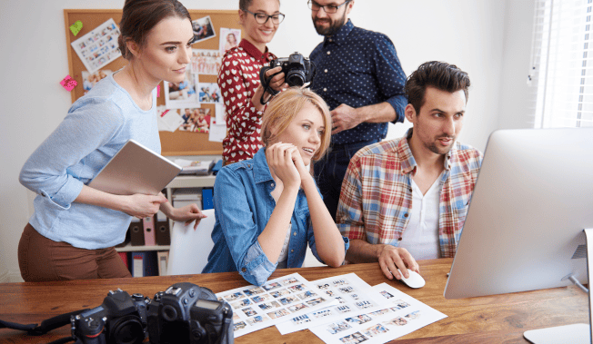 Team of photographers reviewing photos on computer, collaborating on project. - International Awards