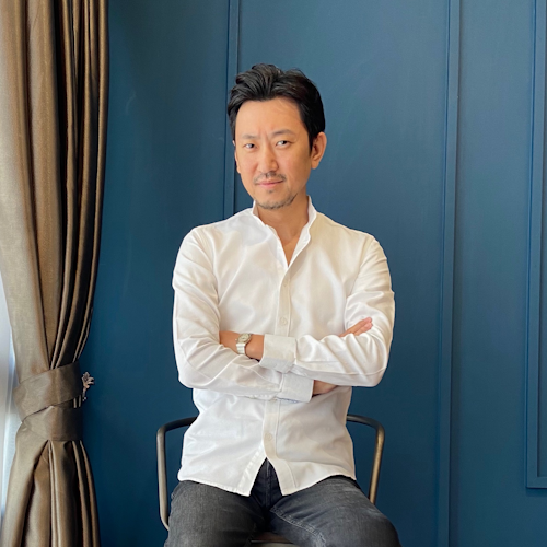 So Iizuka, a man in a white shirt, sits with arms crossed. - International Awards