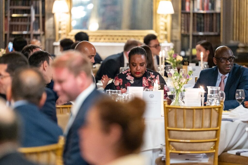 Businesspeople at a formal dinner, woman in floral dress at table - International Awards